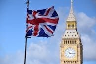 Union Jack flag waving in front of Big Ben, London, against a clear blue sky.